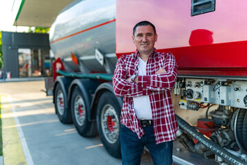 a male tanker or truck driver poses next to his vehicle at a gas station, casually dressed and ready to go - obrazy, fototapety, plakaty