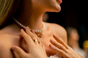 close-up of the neck and collarbones of a girl trying on a beautiful pearl necklace beauty craft...