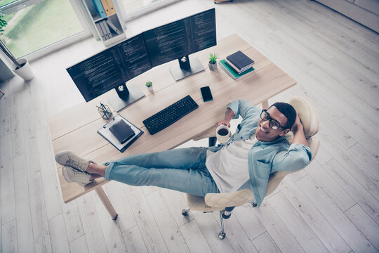 Full body photo upper view shot of dreamy programmer man lying leather boss armchair having coffee break indoors workplace next to computer