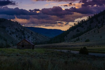 a mountain range with an old cabin on the side of the mountain