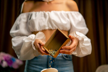 Obraz premium close-up girl designer a needlewoman pours out a box of various beads to create creative craft jewelry necklaces engagement rings earrings bracelets