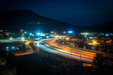 traffic on a highway in the night with mountain backdrop and lights