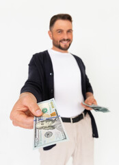 Young successful man holding out his hand with a 100 dollar bill on a white background.