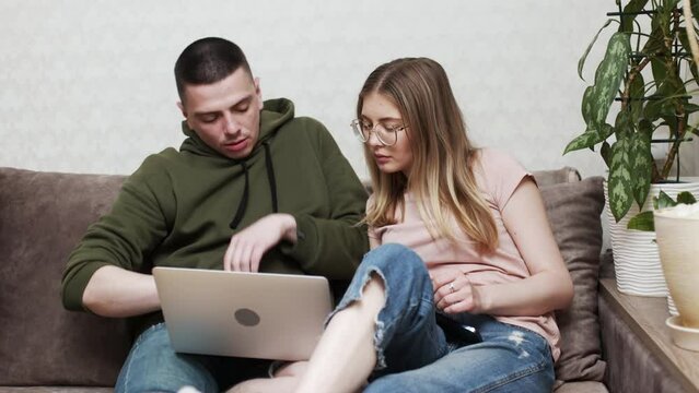 Happy online retail web services buyers make easy purchase, instant money transfer, use secure remote e payment concept. Couple in love sit on sofa with laptop holding credit card buying on internet