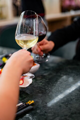 Close up of hands young couple man and woman clinking with glasses of red and white wine at restaurant