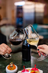 Close up of hands young couple man and woman clinking with glasses of red and white wine at restaurant