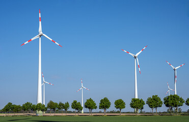 Modern wind turbines with a tree-lined road seen in Germany