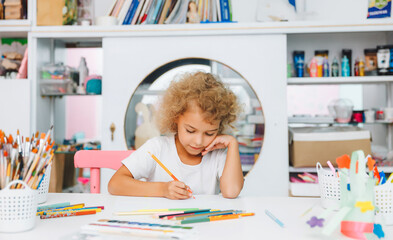 Cute little blonde preschooler girl draws at home