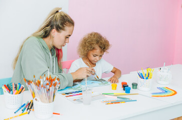 mother and child draw. daughter is engaged in creativity. mother and daughter paint.