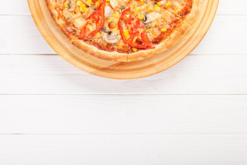 delicious pizza with chicken, mushrooms, cheese, tomatoes and corn on a wooden background