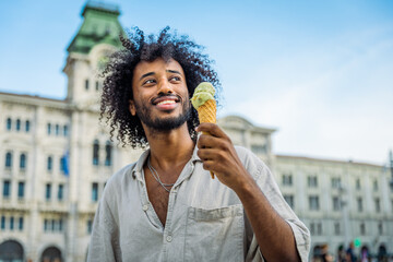 A young man eats ice cream while enjoying his holidays in Trieste
