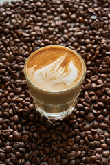 Close-up of a cup of coffee with milk on a ground of roasted coffee beans
