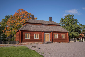 Fototapeta na wymiar Old mansion red log house, autumn colors tree, a sunny day in Stockholm