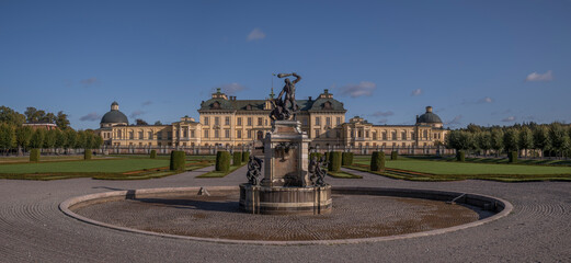 Fototapeta premium Statue and castle and park in the Drottningholm island, autumn colors tree, a sunny day in Stockholm