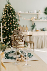Cake with cookies stars Christmas balls and gold gift with bow on the kitchen table