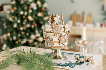 Cake with cookies stars Christmas balls and gold gift with bow on the kitchen table