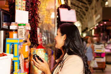 A young Hispanic woman in a market, shopping for spices, holding dried red peppers in her hands