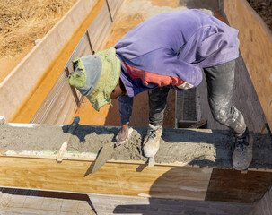 african bricklayer working with trowel, balancing on the edge of the brick wall at the top floor