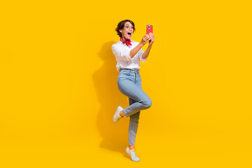 Fototapeta na wymiar Full length photo of overjoyed cheerful girl wear stylish clothes looking camera live stream broadcast isolated on yellow color background
