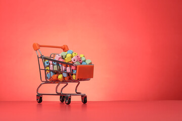 A shopping cart filled with colorful cubes is isolated on the red background.