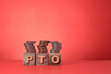 Concept on PTO or paid time off. The letter PTO on wooden blocks, with coins stacked on the wooden blocks. Copy space for message, text, advertisement, etc. 