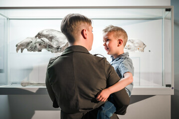Mother and her little son enjoying watching an exhibition in a natural history museum. Children and family time in museums concept.