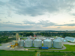 Obraz premium Aerial view silver silos on agro manufacturing plant for processing drying cleaning and storage of agricultural products, flour, cereals and grain. Large iron barrels of grain. Granary elevator