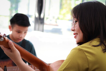 Happy Asian mother and son playing music together at home. Studying music. Concert. Band