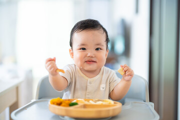 離乳食後期でをつかみ食べをしてご機嫌な生後9か月の赤ちゃん