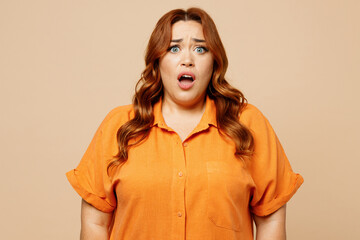 Young sad shocked ginger chubby overweight woman she wear orange shirt casual clothes look camera...