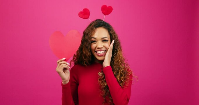 Surprised young woman finds love, shocked face looking at heart, studio