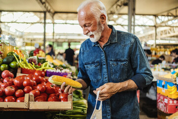 Senior man shopping at the farmer's market. One elderly man buying a fresh vegetable at a community...
