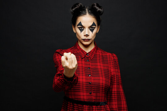 Young woman with Halloween makeup face art mask wear clown costume red dress stretch hand to camera pov come here isolated on plain solid black background studio portrait. Scary holiday party concept.