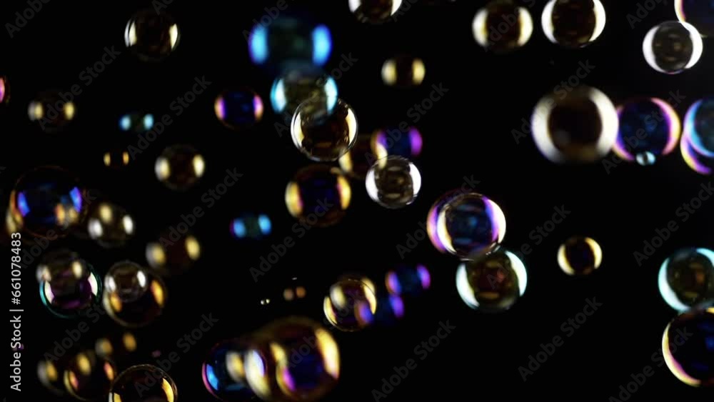 Poster colorful soap bubbles fly in empty space on isolated black background. colorful lights. many rainbow