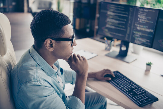 Photo of serious programmer young man working on outsource startup company researching and thinking program code indoors workspace