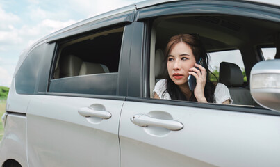 Stressed and confused Asian woman calls insurance on faulty car while traveling together