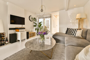 a living room with couches, coffee table, and television on the wall in the room is very white