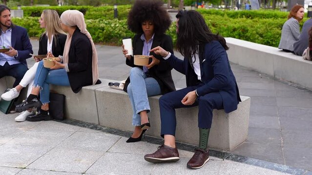 Multiracial business people eating together outside of office during lunch break - Focus on the man with prosthetic leg