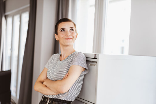 Contemporary Office Contemplation: Stylish Short-Haired Woman Leaning Thoughtfully by the Cabinet