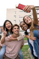 Cheerful funny group of friends taking a selfie laughing.Multiracial young people having fun and taking pictures outside.
