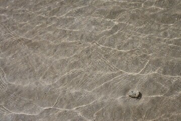 白い砂浜と晴れた日の光が当たった浅瀬の海