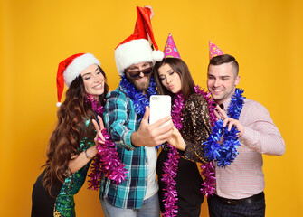 group or company of friends in santa hat, party hats, boas celebrating Christmas, having fun,...