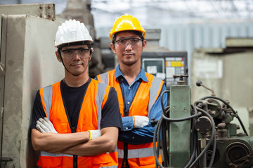 Portrait of asian man engineer wear yellow helmet and uniform standing at industrial workshop. handsome workmen ​in factory. Copy space.