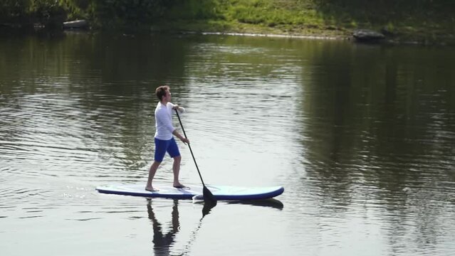 Caucasian man on the board. a man with glasses stands and rows an oar on a board. the man is swimming. water sports. Record high quality video in Full HD format.
