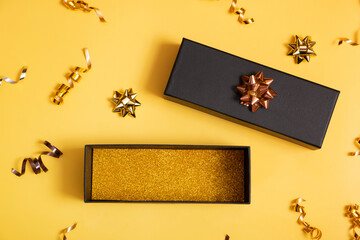 Black friday sale concept. Black gift box with copy space and festive decorations on yellow...