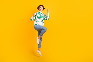Fototapeta na wymiar Full length legs body photo of awesome victory competitor young girl jumping fists up jump triumphant isolated on yellow color background