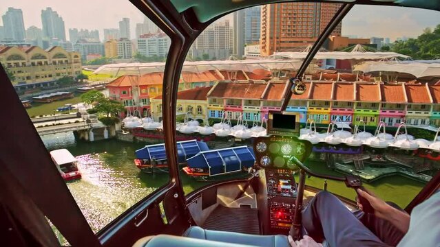 Helicopter cockpit interior flying on Clarke Quay and Riverside area in Singapore. Scenic flight above waterfront skyline with cruise boat on Singapore River in a sunny day.