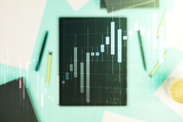 Abstract creative financial graph and modern digital tablet on desktop on background, top view, financial and trading concept. Multiexposure