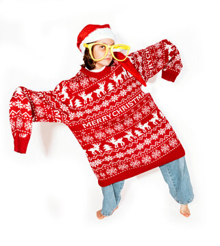 Girl with Christmas jumper, santa hat and big glasses dancing in white studio