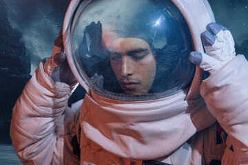 Male astronaut in spacesuit touching helmet with closed eyes while standing in spaceship